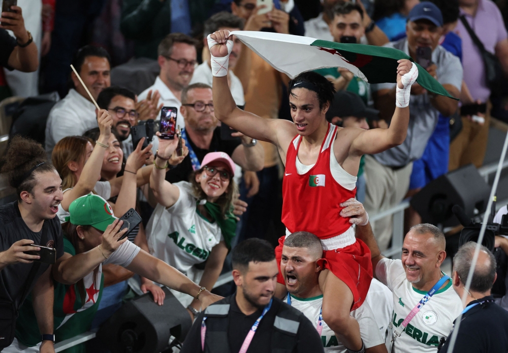 Imane Khelif of Algeria holds an Algerian flag as she celebrates winning against Liu Yang of China. — Reuters pic