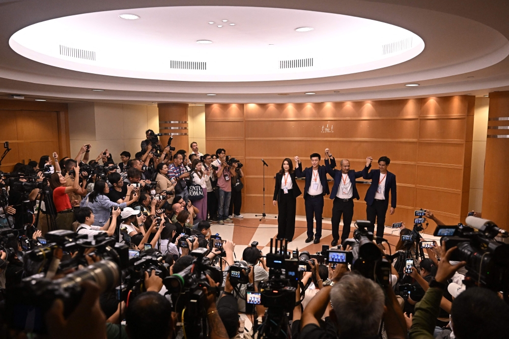 Natthaphong Ruengpanyawut (2nd left), leader of the relaunched Thai opposition party ‘Prachachon,’ known as ‘People's Party’ in English, joins hands with party members during a press conference at the Thai Summit Tower in Bangkok on August 9, 2024, after the Constitutional Court ruled to dissolve the Move Forward Party for campaigning to reform defamation laws. — Reuters pic  