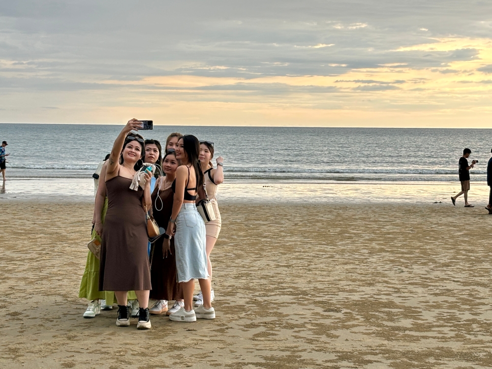 South Korean tourists enthusiastically taking photos of themselves at the Kota Kinabalu beach in the evening as the sun is about to set. — Picture by Julia Chan