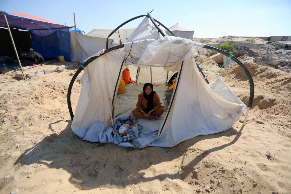 A displaced Palestinian woman and a child shelter in a cemetery, as Gaza health ministry announced that death toll has surpassed 40,000, amid the Israel-Hamas conflict, in Khan Younis, in the southern Gaza Strip, August 15, 2024. — Reuters pic  