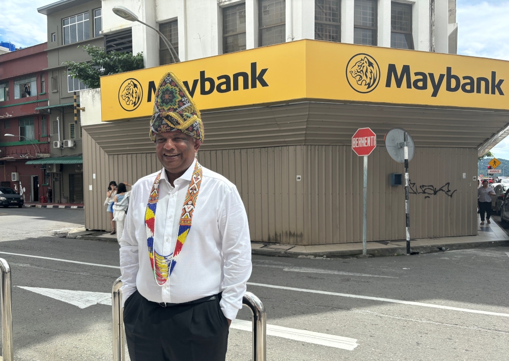 Tan Sri Tony Fernandes poses in front of the closed Maybank brank on Jalan Pantai in Kota Kinabalu. — Picture by Julia Chan