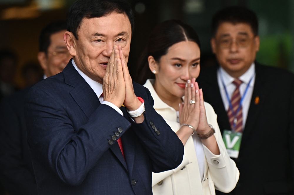 Former Thai prime minister Thaksin Shinawatra greets supporters with his youngest daughter Paetongtarn Shinawatra (right), known by her nickname ‘Ung Ing,’ after landing at Bangkok’s Don Mueang airport on August 22, 2023. — AFP pic