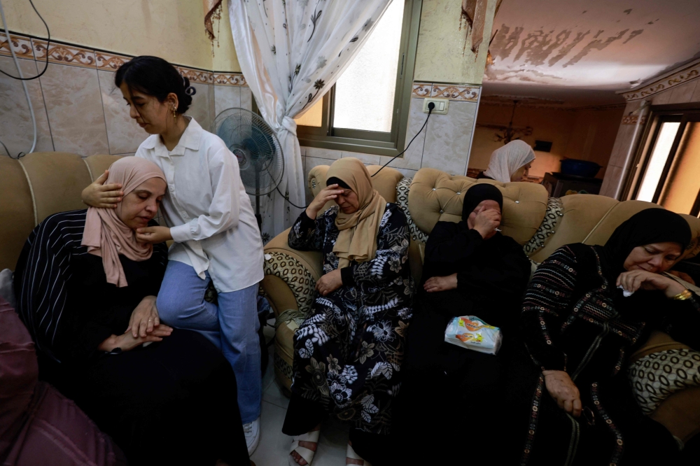 A young girl comforts the mother of a 23-year-old Palestinian man, a day after he was killed during an attack by Jewish settlers on the village of Jit near Nablus in the occupied West Bank, on August 16, 2024. Negotiators trying to hash out a Gaza ceasefire deal were due to meet for a second day in Qatar today, after the deadly Jewish settler attack on the Palestinian village drew widespread rebuke, including from Israeli officials. — AFP pic