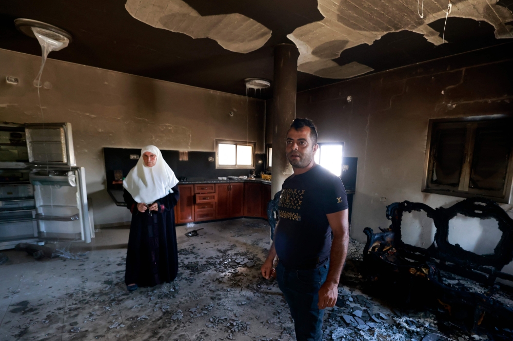 People stand inside their damaged home, a day after an attack by Jewish settlers on the village of Jit near Nablus in the occupied West Bank that left a 23-year-old man dead and others with critical gunshot wounds August 16, 2024. — AFP pic