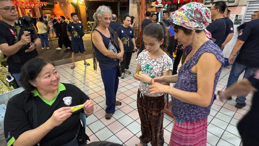 A believer guides tourists on how to fold joss papers. — Photo by Voon Siang Pin