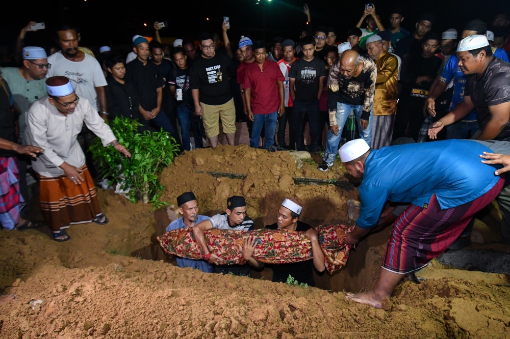 The remains of Istiqomah Ahmad being laid into her grave at the Bandar Pasir Mas Islamic Cemetery in Kelantan on August 19, 2024. — Bernama pic