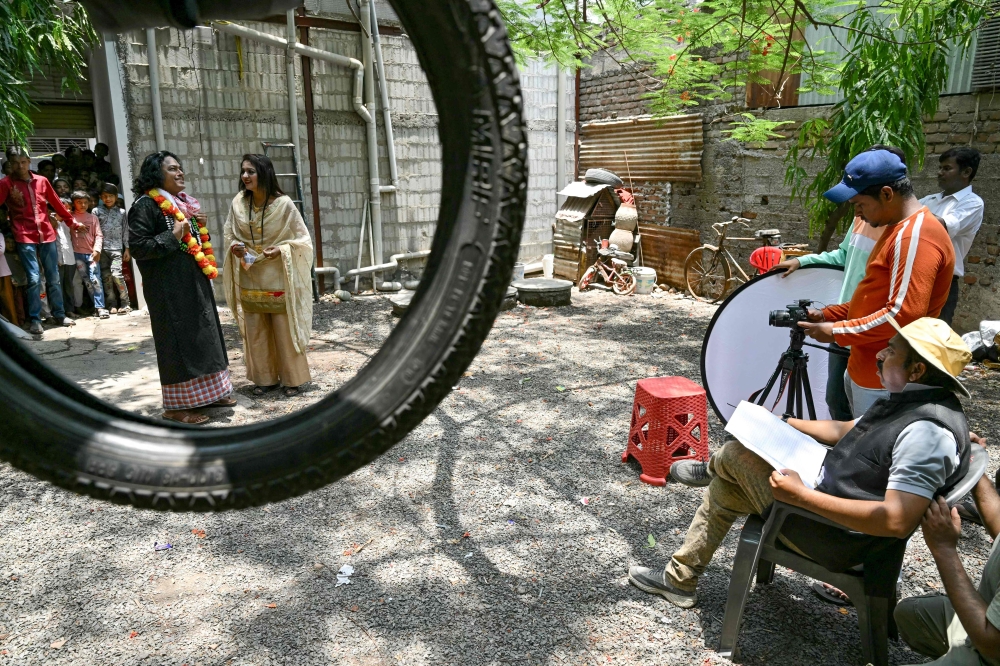 n this photograph taken on May 23, 2024 actors Aleem Tahir and Roma Momin perform as director Muqeem Meena Nagri watches as they shoot a movie in Malegaon. — AFP pic