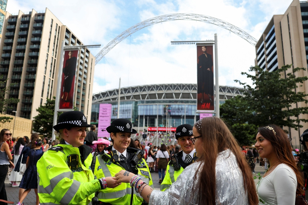 A fan hands a friendship bracelet to a police officer, on the day of a Taylor Swift concert, following the cancellation of three Taylor Swift concerts in Vienna because of a planned attack, outside Wembley Stadium in London August 15, 2024. — Reuters pic  