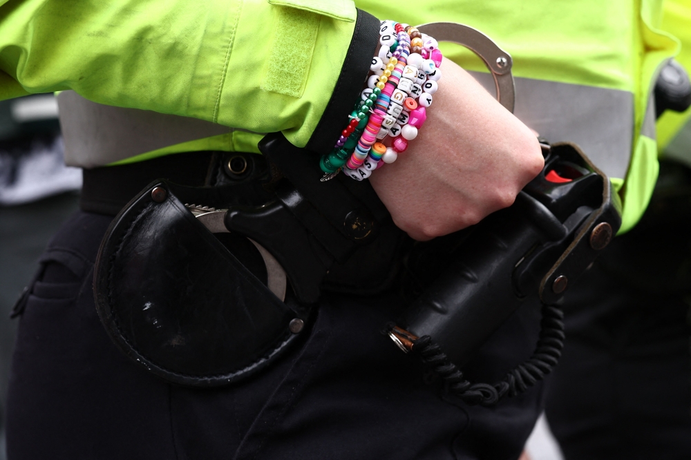 A police officer wearing friendship bracelets talks to fans of US mega-star Taylor Swift, so-called Swifties, as they gather on Olympic Way outside Wembley Stadium in London on August 15, 2024, ahead of the first of five concerts she is playing at the stadium. — AFP pic