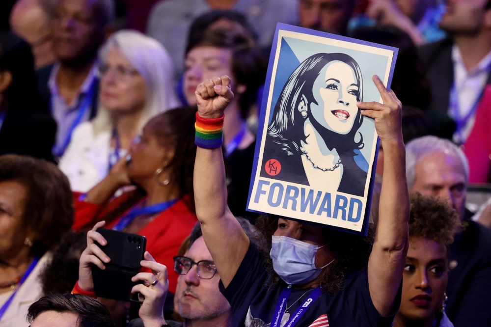 A attendee with holds up a post of Democratic presidential nominee and US Vice President Kamala Harris on Day 3 of the Democratic National Convention (DNC) in Chicago, Illinois August 21, 2024. — Reuters pic  