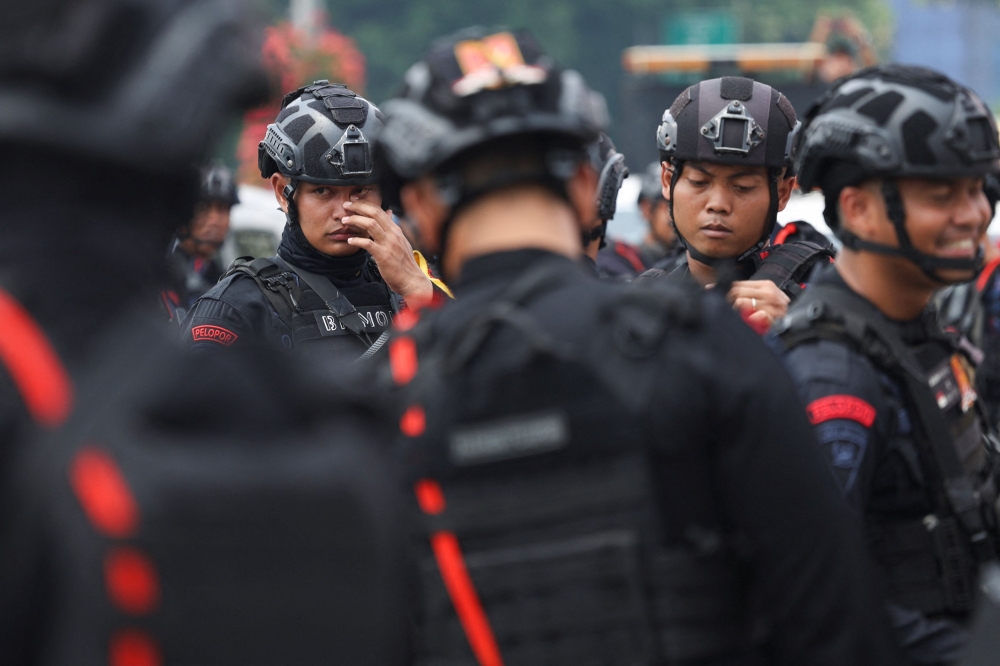 Riot police guard during a protest outside the Indonesian parliament today. — Reuters pic