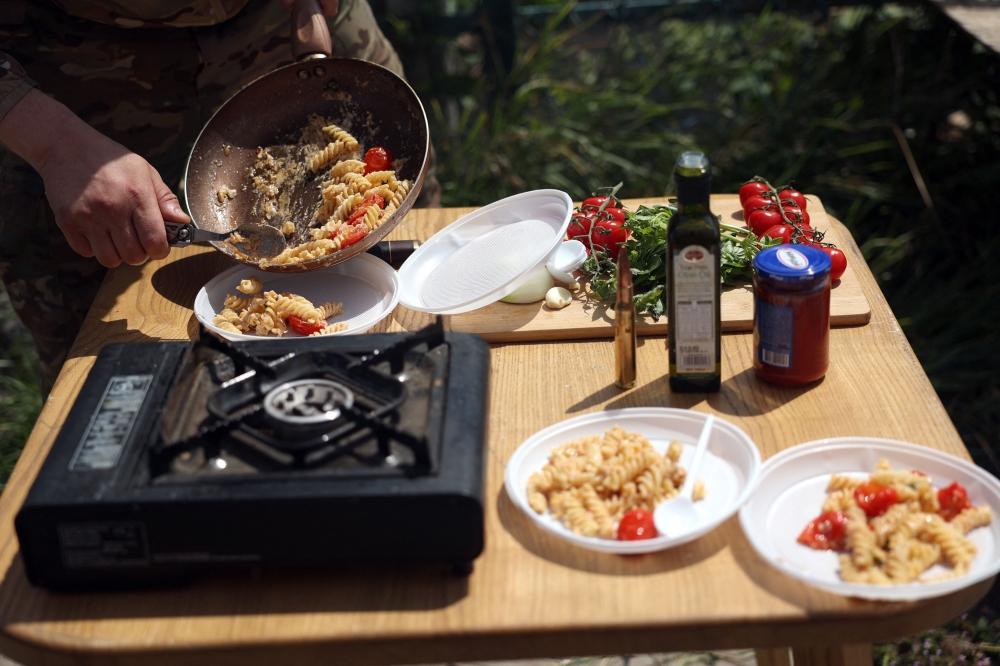 Ukrainian serviceman and influencer Ruslan Mokrytskyi serves pasta he prepared during a video recording for Tik Tok in an undisclosed location in the Donetsk region July 27, 2024. — AFP pic