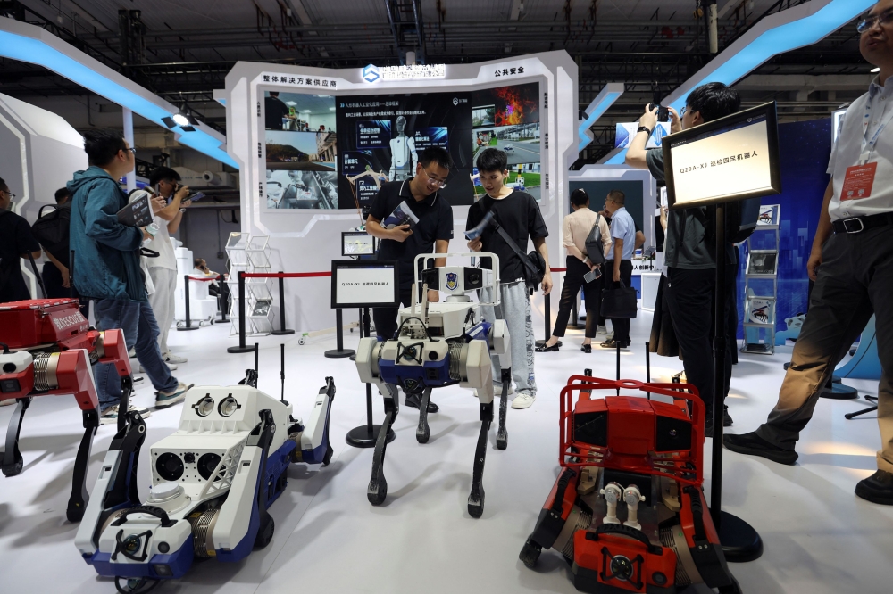 Visitors look at a police patrol robot displayed at the World Robot Conference in Beijing, China. — Reuters pic