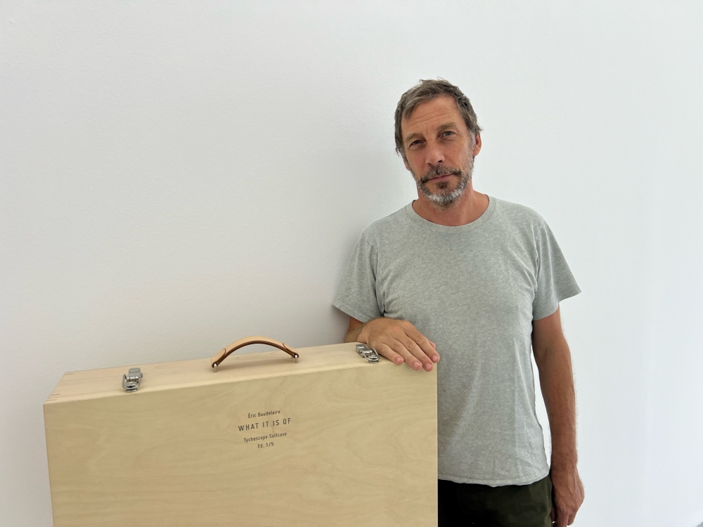 French artist Éric Baudelaire and the box suitcase that holds the whole exhibition. — Picture by Opalyn Mok