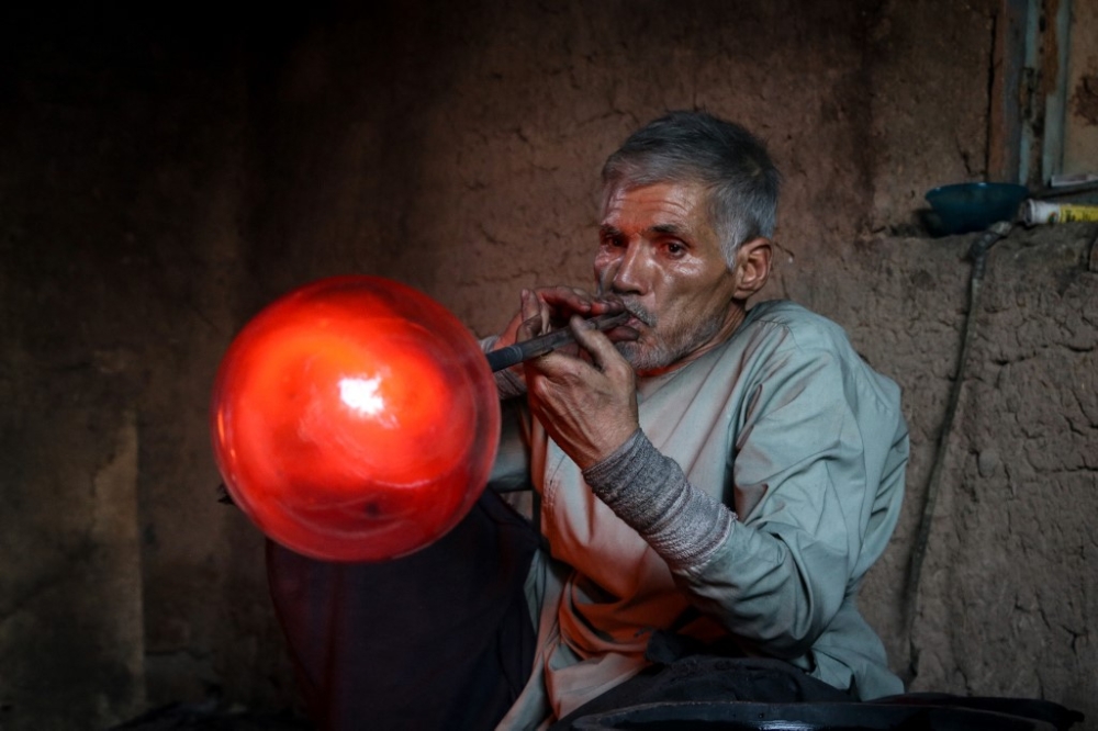 In this photograph taken on August 11, 2024, Ghulam Sakhi Saifi, an Afghan glassblower, crafts a glassware at his traditional workshop in Afghanistan’s western city of Herat. Seated in front of a searing furnace, Saifi teases forth sinews of molten blue glass — the guardian of an Afghan glassblowing trade refusing to break with tradition. — AFP pic