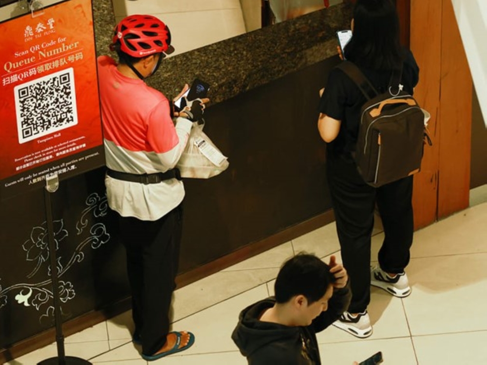 A food delivery rider waiting to collect his order at a food court in Tampines.