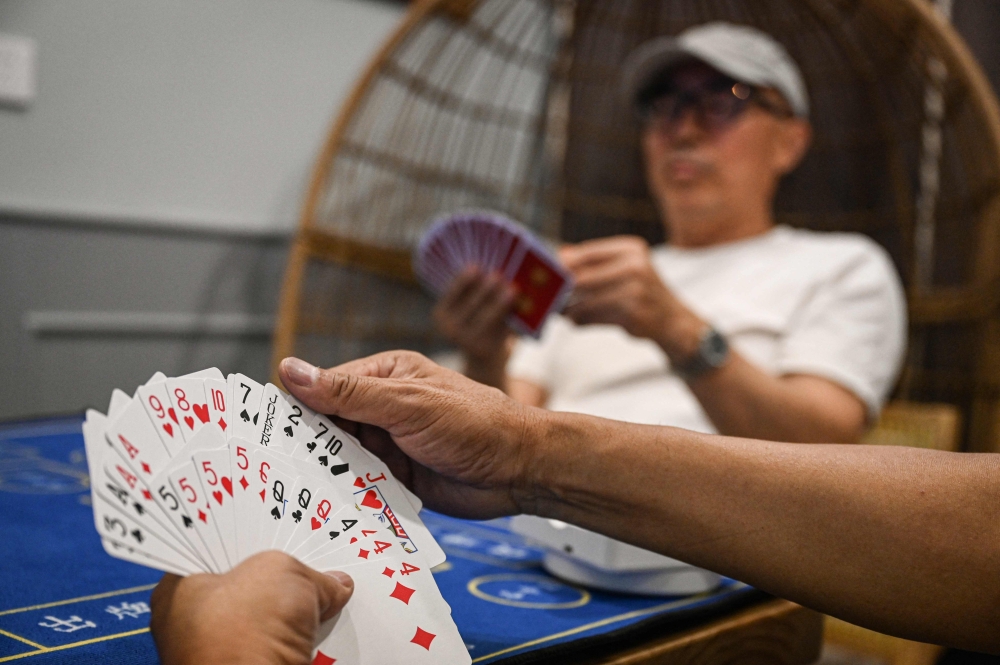 This photo taken on August 15, 2024 shows Tang Songyuan (background), who runs a clubhouse where people gather for Guandan or ‘throwing eggs’, playing the card game with others in Hangzhou, in eastern Zhejiang province. In the evenings in the Chinese city of Hangzhou, friends meet to ‘throw eggs’ — a card game winning fans despite official warnings that it is an addictive waste of time and a drain on productivity. — AFP pic