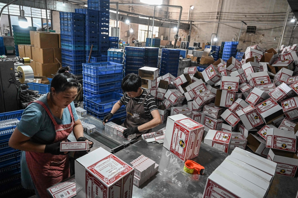 This photo taken on August 14, 2024 shows employees packaging playing cards at a factory in Wuyi, in eastern China’s Zhejiang province. — AFP pic