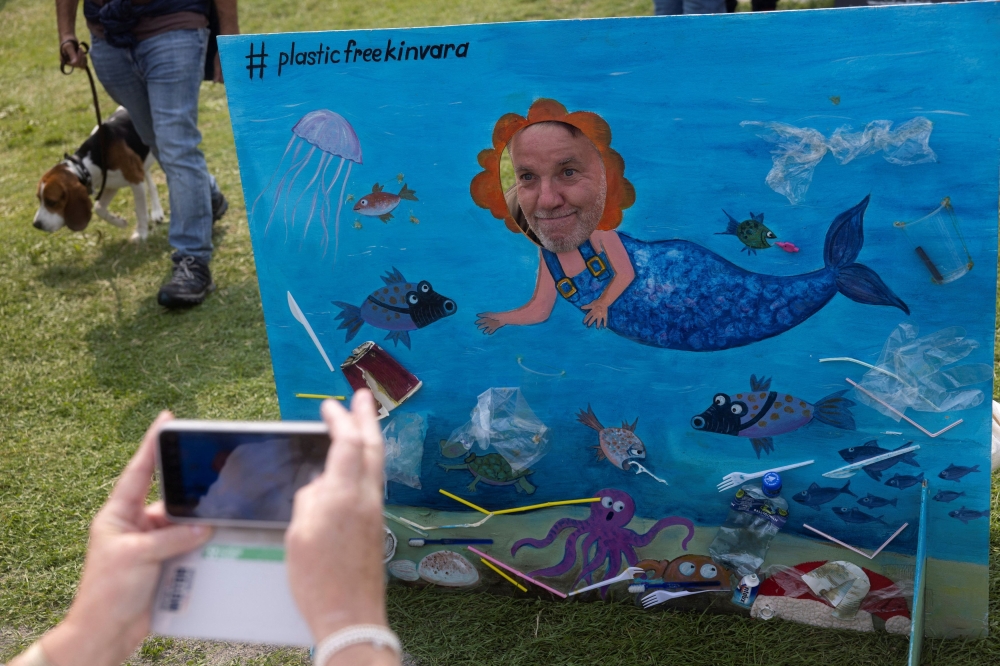 A man poses in front of a board depicting plastic pollution in the sea to create awareness during an annual seaweed race at the Cruinniu na mBad (gathering of the boats) regatta in Kinvara, Ireland August 18, 2024. — Reuters pic  