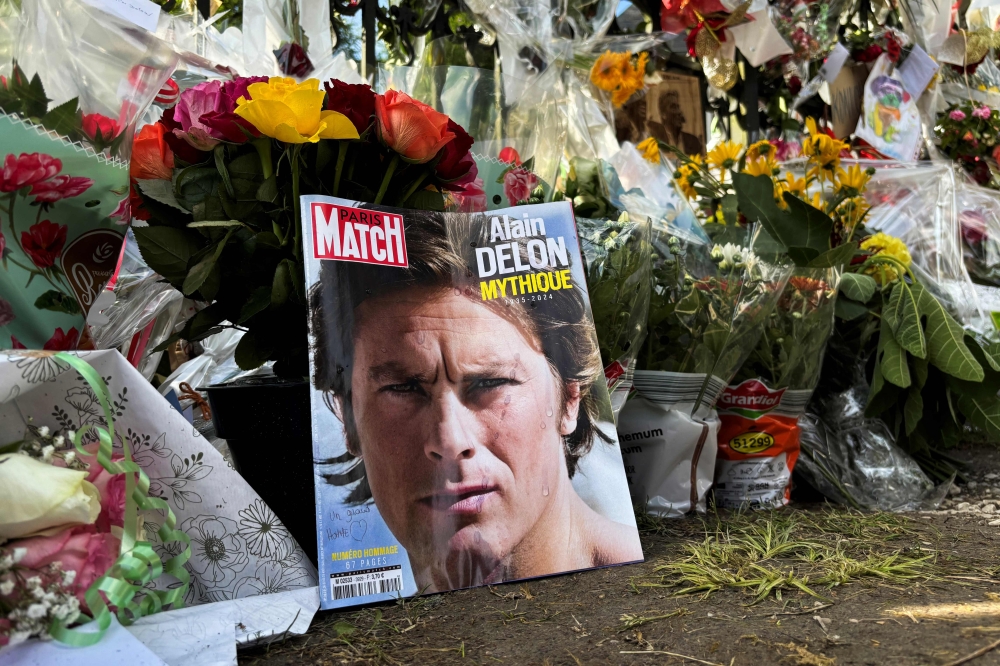 French film legend Alain Delon laid to rest near dogs, as mourning fans leave flowers and cards at manor gates