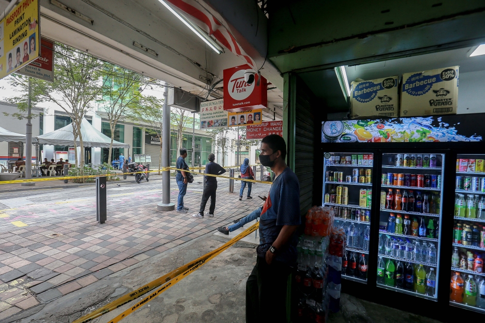 A shop worker looks out of a store that is open despite a nearby sinkhole that appeared at Jalan Masjid India August 25, 2024. — Picture by Sayuti Zainudin