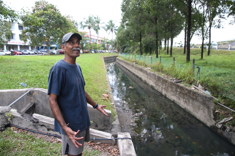 Taman Sri Muda Zone D Residents Association chairman Andrew De Silva in front one of Taman Sri Muda's drainage. — Picture by Yusof Mat Isa