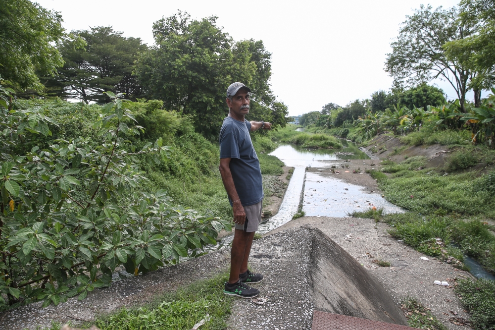 Taman Sri Muda Zone D Residents Association chairman Andrew De Silva pointing out the shallow water entry point to the Klang river. — Picture by Yusof Mat Isa