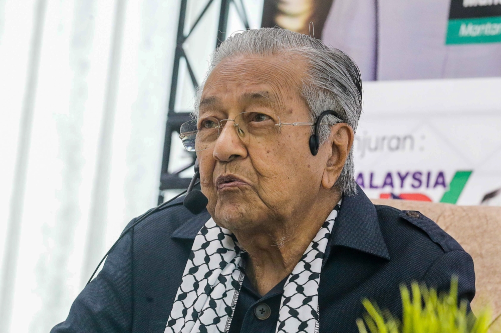 Former prime minister Tun Mahathir Mohamad now requires an earpiece to hear clearly, and a magnifying glass to read small prints. — Picture by Sayuti Zainudin