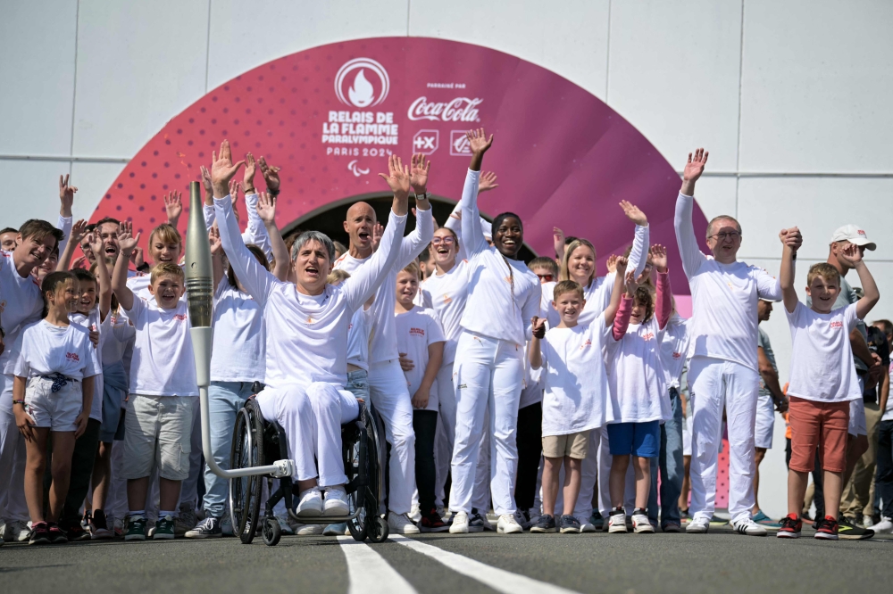 Former French wheelchair fencer Emmanuelle Assmann with the torch of the Paris 2024 Paralympic Games on her wheelchair after arrival of the Paralympics flame at the entrance of the Channel Tunnel in Coquelles, northern France. — AFP pic