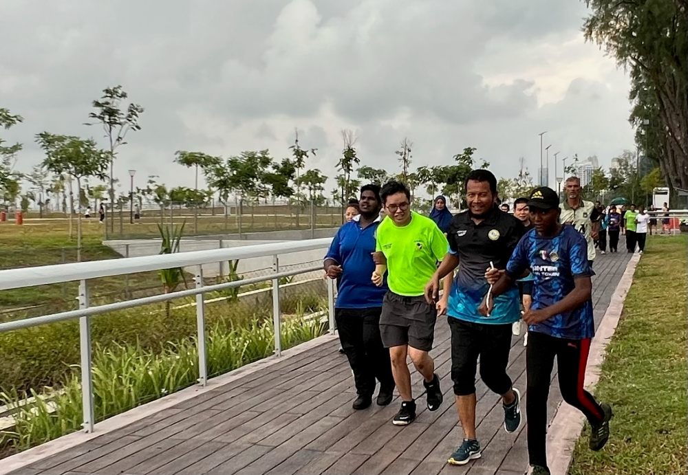 John Fung (in fluorescent T-shirt) running with roommate S.Puvarasan (far left) at Gurney Bay. — Picture by Opalyn Mok