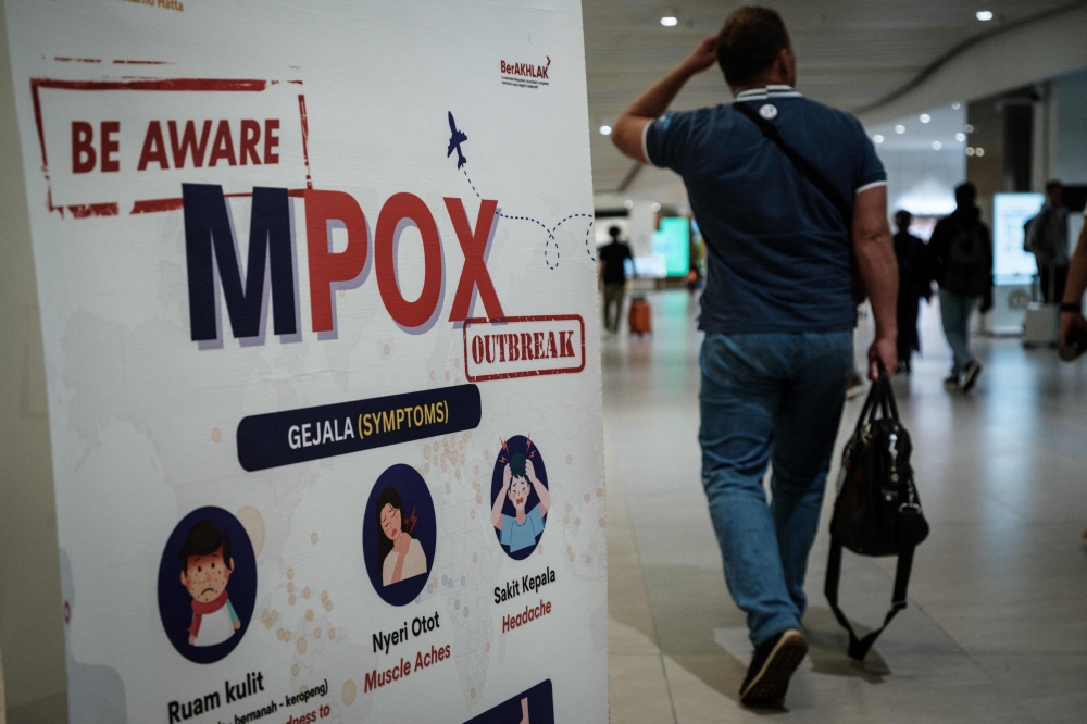 A passenger walks past a banner informing about mpox at Soekarno-Hatta International Airport in Tangerang on August 26, 2024. — AFP pic