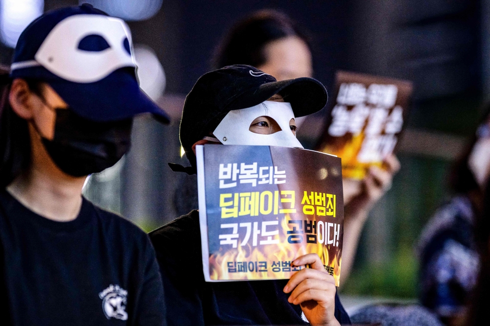 Activists wearing eye masks, hold posters reading ‘Repeated deepfake sex crimes, the state is an accomplice too’ during a protest against deepfake porn in Seoul August 30, 2024. — AFP pic