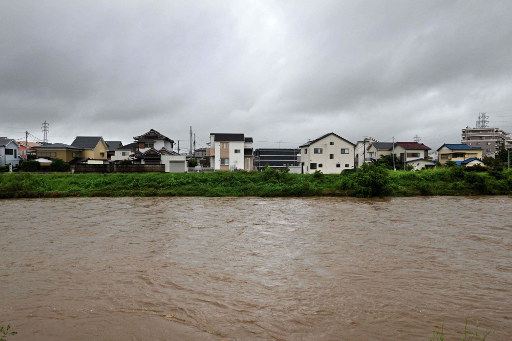 Muddy waters of the Kaneme River flow past houses lined up behind the river's bank in the aftermath of Typhoon Shanshan in Hiratsuka City, Kanagawa prefecture on August 30, 2024. — AFP pic