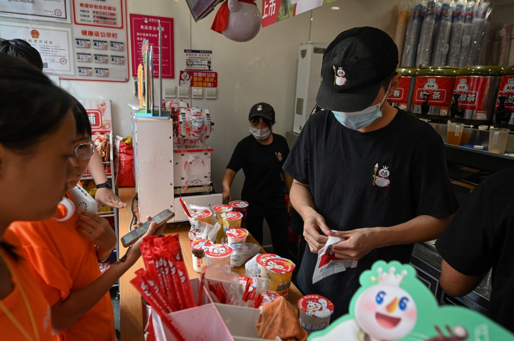 This photo taken on August 2, 2024 shows employees of bubble tea chain Mixue Bingcheng preparing drinks for customers in Beijing. — AFP pic