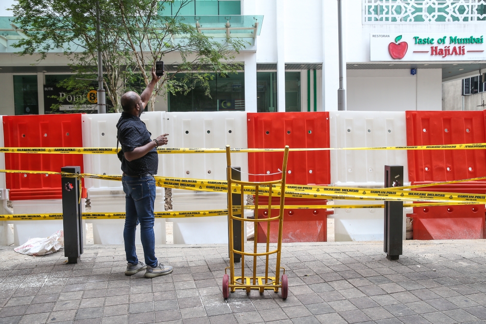 A man takes pictures with his cellphone of a sinkhole at Jalan Masjid India in Kuala Lumpur September 1, 2024. — Picture by Yusof Mat Isa