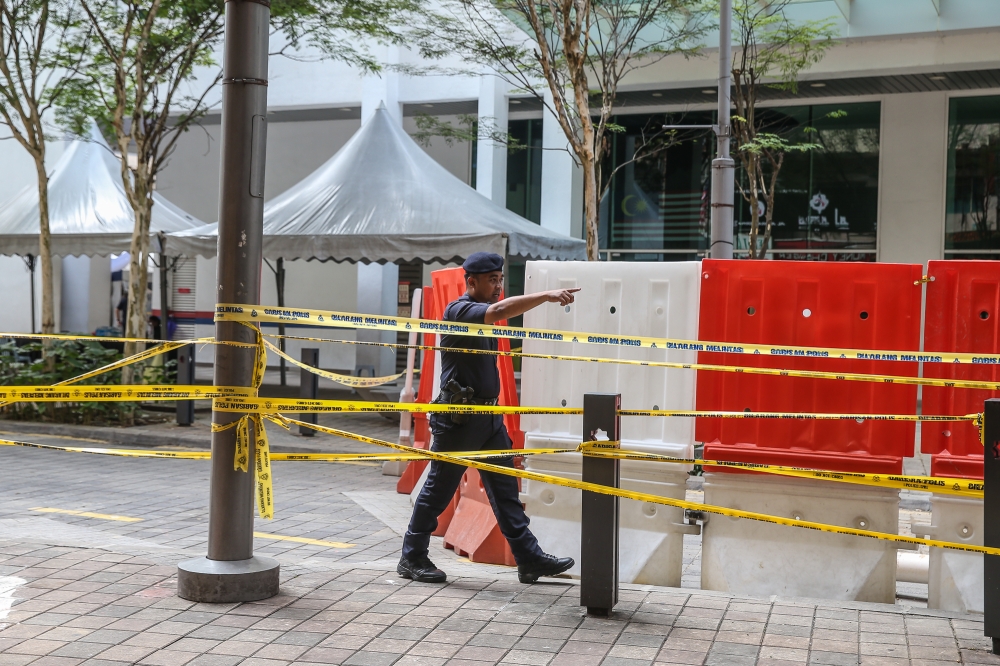 A policeman issues a warning to passers-by near a sinkhole at Jalan Masjid India in Kuala Lumpur September 1, 2024. — Picture by Yusof Mat Isa