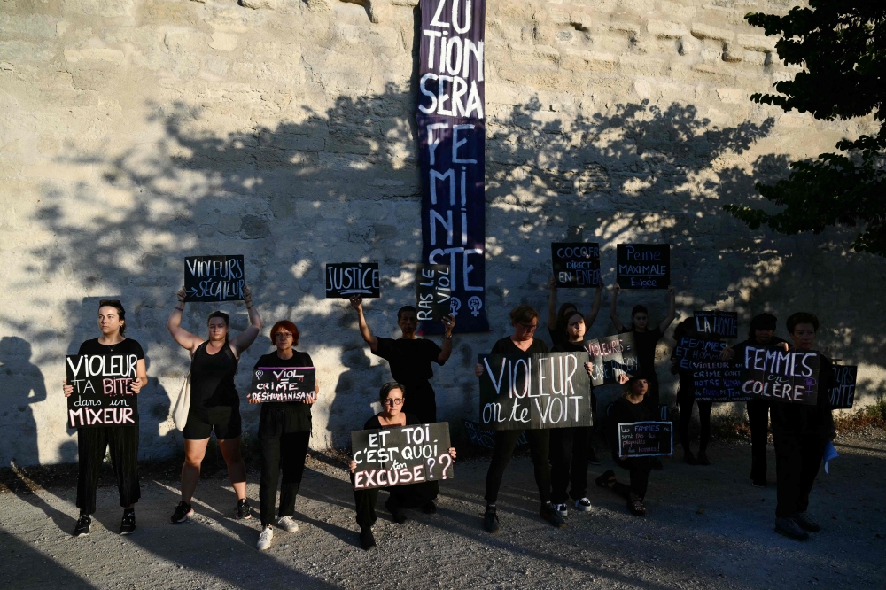 Demonstrators hold placards during a protest outside the courthouse during the trial of a man accused of drugging his wife for nearly ten years and inviting strangers to rape her at their home in Mazan, a small town in the south of France, in Avignon, on September 2, 2024. — AFP pic