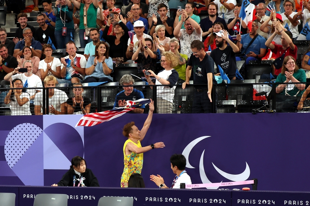 Cheah Liek Hou celebrated his triumph by embracing his coach, Nova Armada, and then proudly waving the Jalur Gemilang around the venue. — Bernama pic