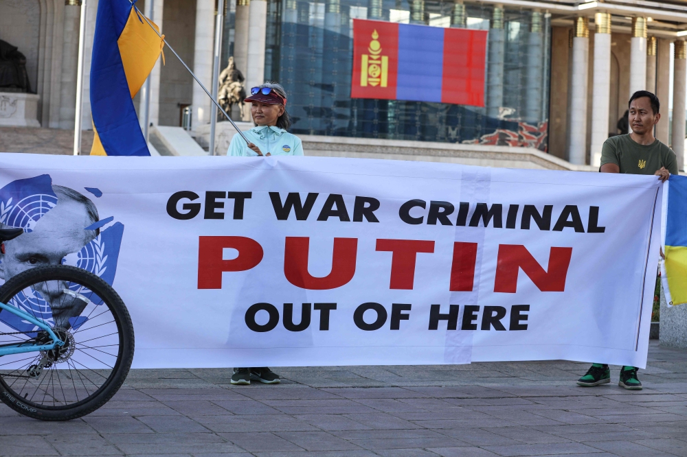 People holding Ukranian national flags and a banner take part in a protest ahead of a visit by Russian President Vladimir Putin in Ulaanbaatar, Mongolia's capital city on September 2, 2024. — AFP pic