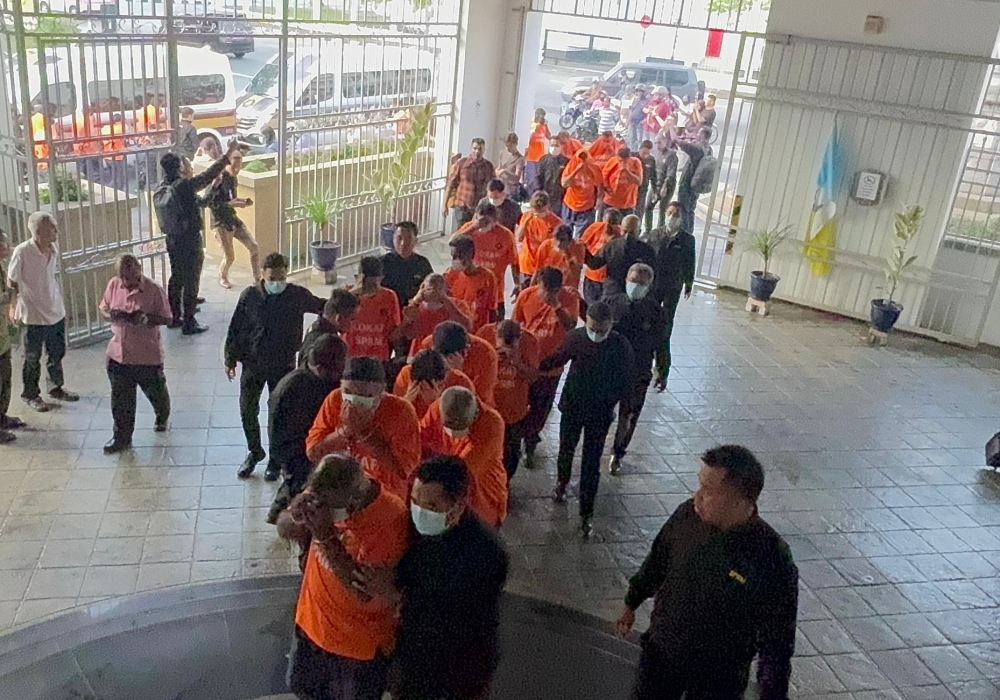 The 33 individuals (in orange) are seen arriving at the George Town magistrates court for the remand applications against them, on September 4, 2024. — Picture by Opalyn Mok