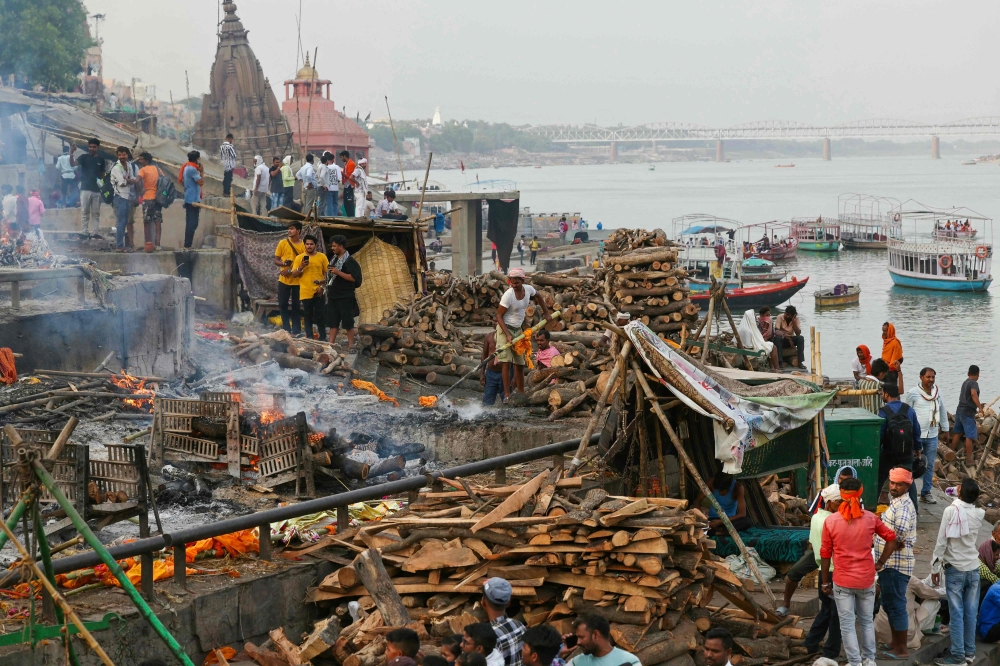 In this photograph taken on June 16, 2024, a cremator (centre) of the Dom community cleans a pyre after funeral rites, at Harishchandra Ghat along the banks of river Ganges in Varanasi. — AFP pic 