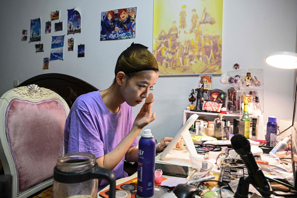 Cosplayer Xu Yunting applying makeup to transform to Jesse, a male character from the video game ‘Light and Night’, before going on a ‘cos commissioning’ date in Shanghai. — AFP pic 