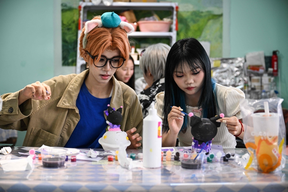 Cosplayer Xu Yunting (left), dressed as Jesse, a male character from the video game ‘Light and Night’, and Feng Xinyu visiting a crafts shop during their ‘cos commissioning’ date in Shanghai. — AFP pic 