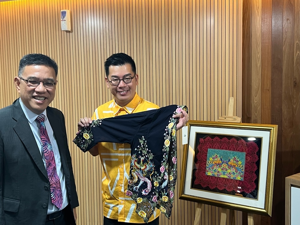 Kenny Loh shows one of his award-winning ‘kebaya’ designs to Penang state exco Wong Hon Wai. — Picture by Opalyn Mok