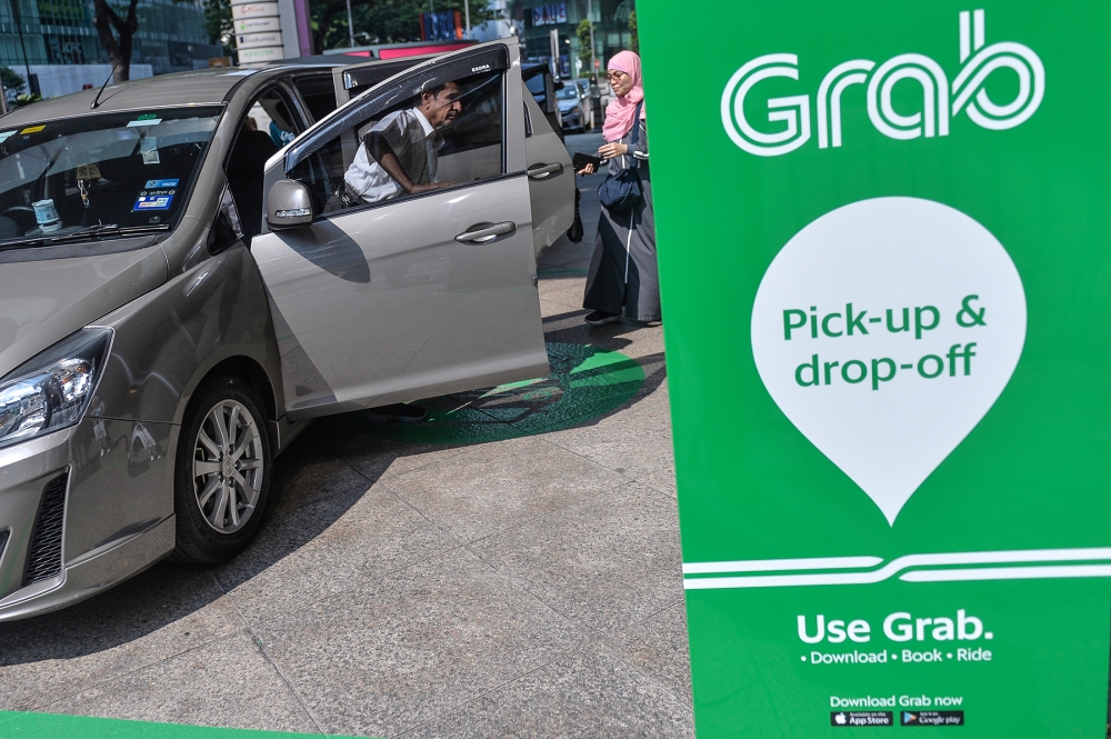 A file photograph shows passengers boarding a vehicle with the GrabCar e-hailling platform, in Kuala Lumpur on July 12, 2019. — Picture by Mukhriz Hazim