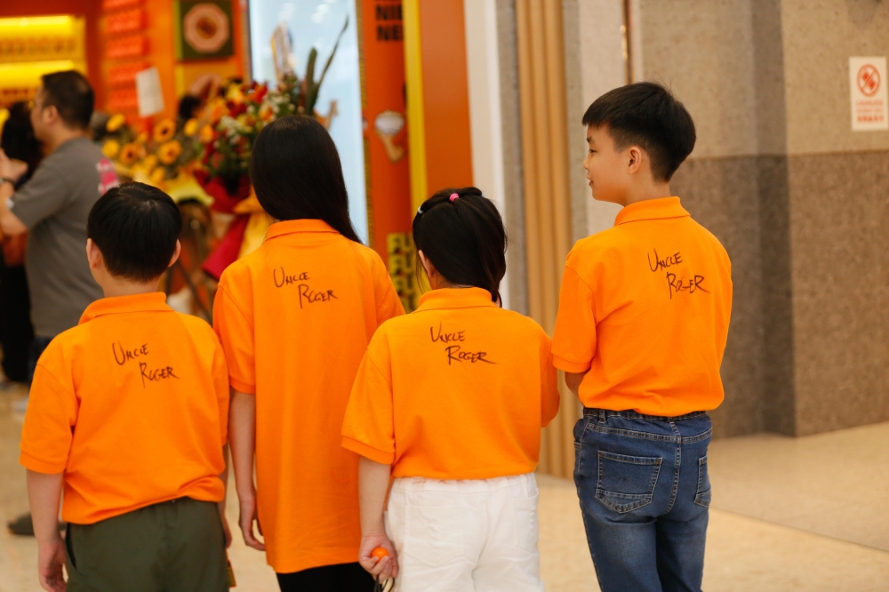 Children wearing orange shirts signed by Uncle Roger attend the grand opening of his first restaurant. — Picture by Raymond Manuel