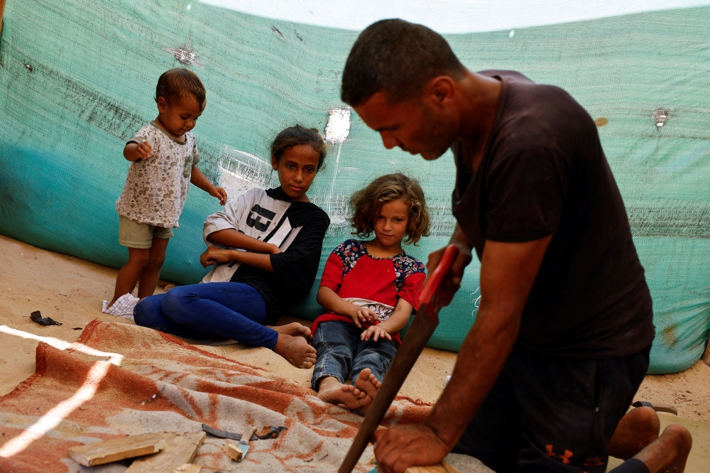 Palestinian Saber Dawas crafting wooden sandals for his daughters. — Reuters pic