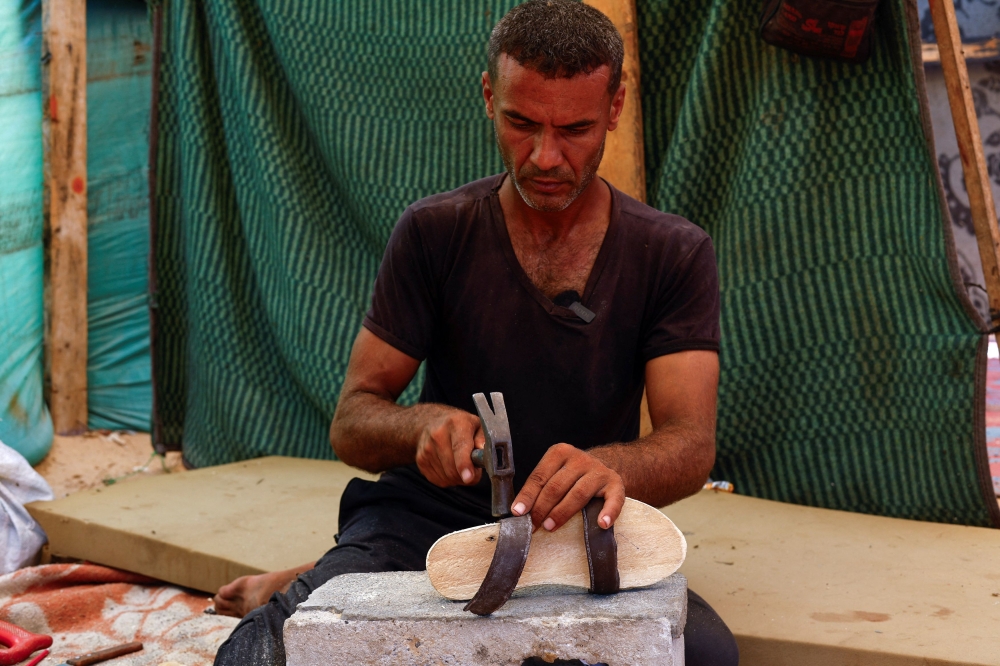 After finding the price of sandals too expensive, Dawas chose to make wooden sandals for his daughters, so they don’t have to go barefoot amid the ruins of Gaza. — Reuters pic