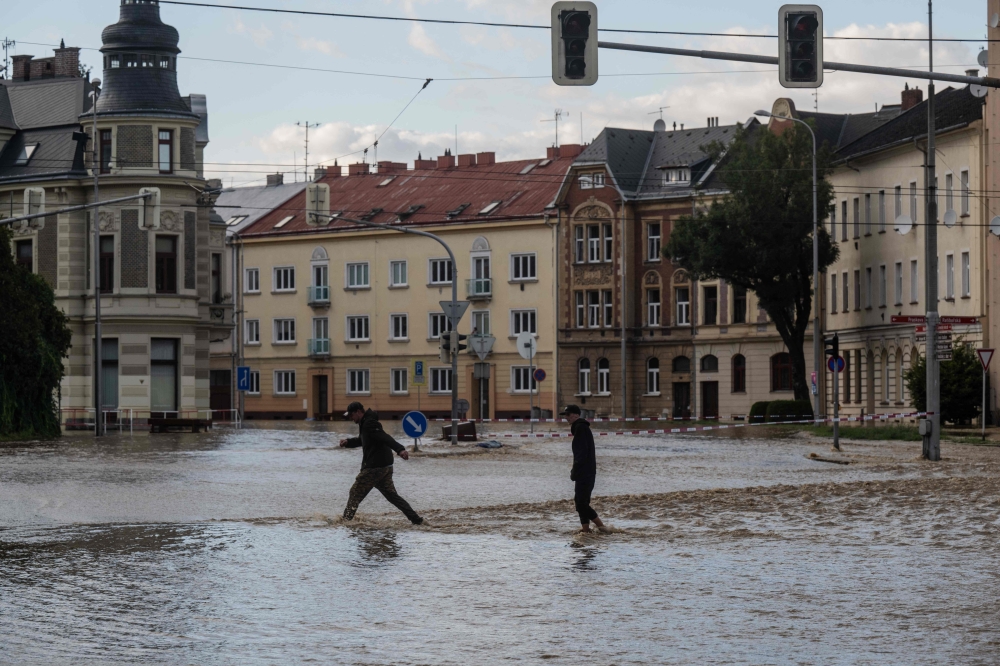 People walk accross a flooded street in Opava, Czech Republic on September 15, 2024. — AFP pic