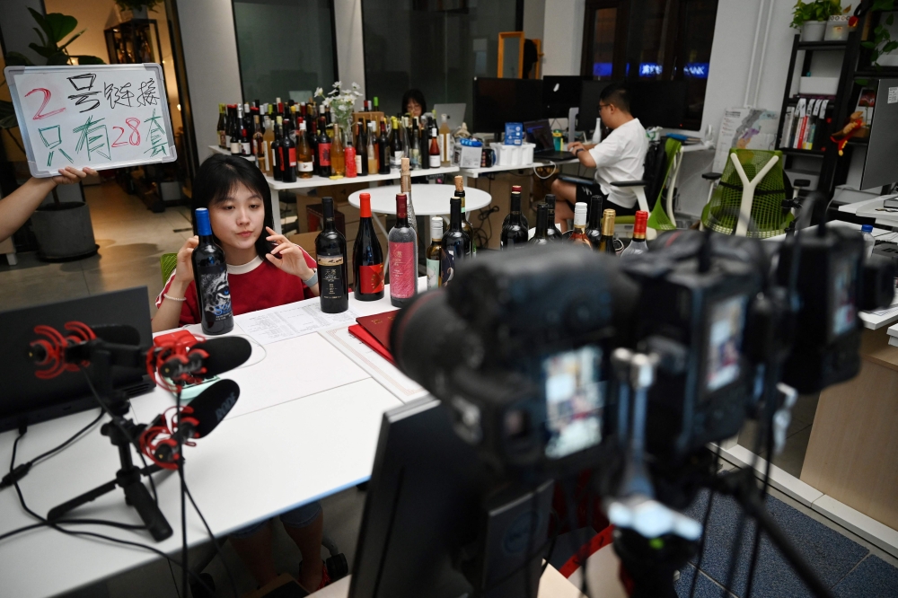 Wine influencer Zhu Lili livestreams a wine review to multiple platforms from her office in Beijing. — AFP pic